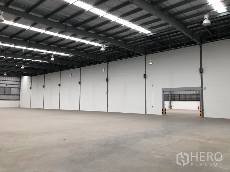 Factory for rent in Bang Sao Thong, Samut Prakan - Open warehouse space with insulated roof, white partition wall and pendant lights.
