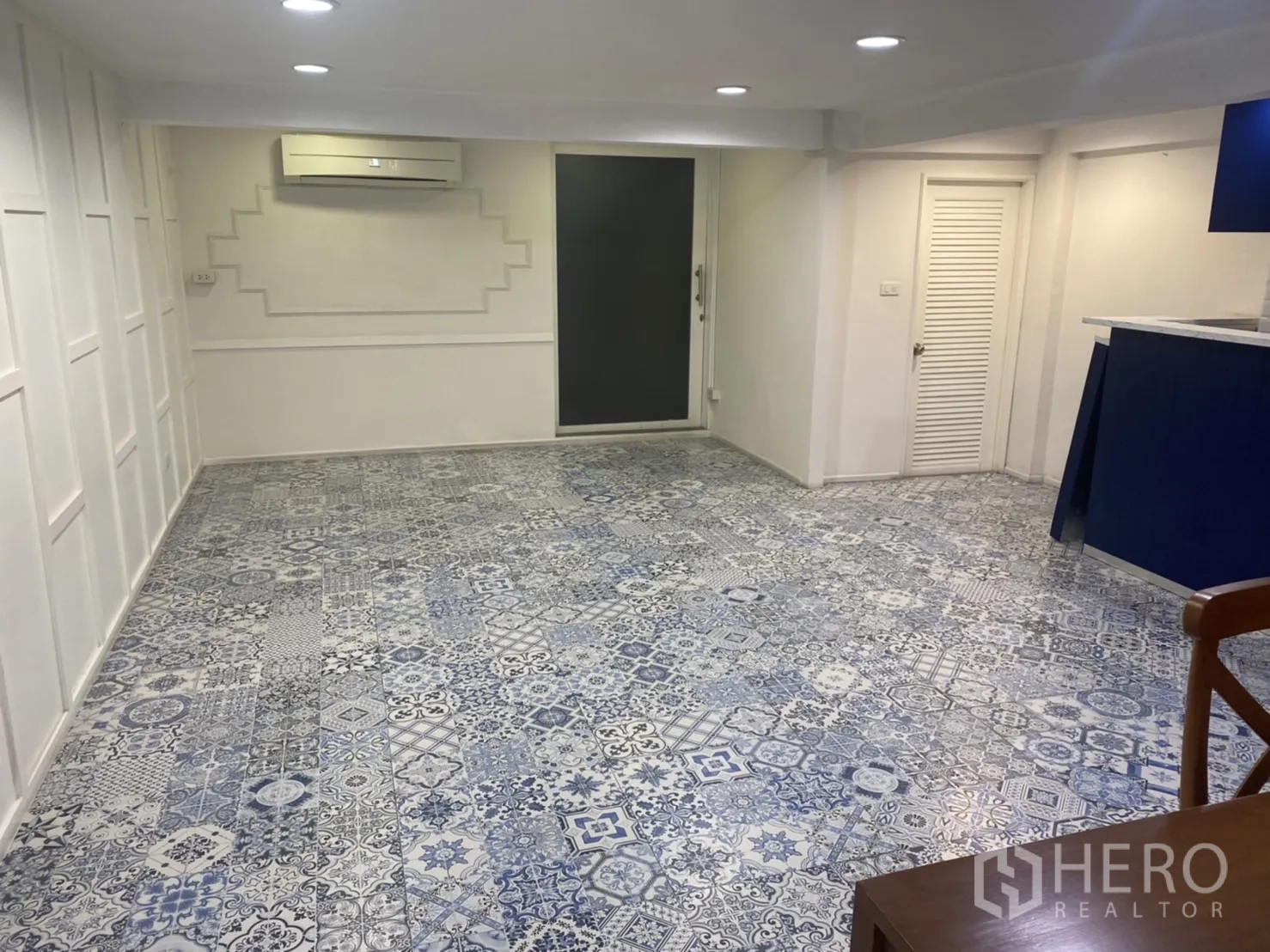 Retail Space for rent in Bang Rak, Bangkok - Spacious retail floor with air conditioning, patterned tiles and a rear door beside the blue counter.