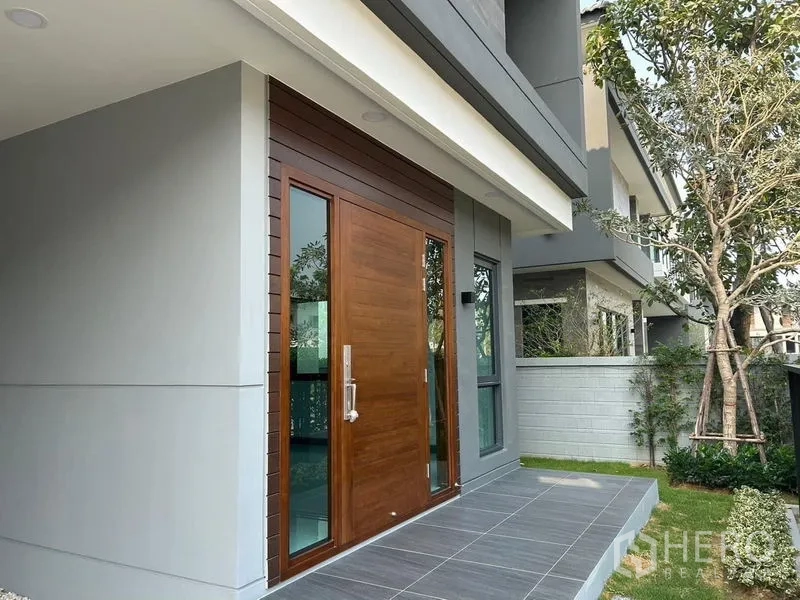 Detached House for rent in Bang Phli, Samut Prakan - Front entrance with solid wood door, side windows and a small landscaped yard.
