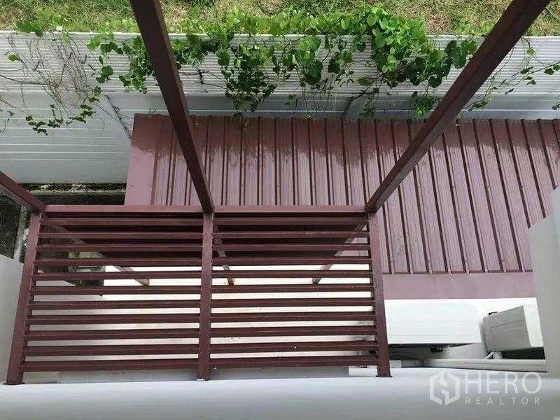 Townhouse for sale in Suan Luang, Bangkok - View of metal balcony and awning with greenery along the boundary wall.