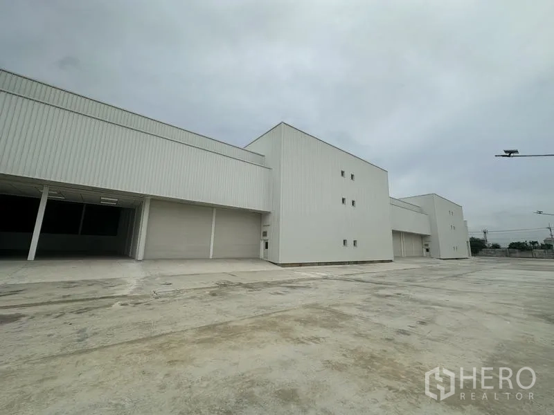 Factory for rent in Pathum Thani - Side view of modern warehouse façades with large roller shutters and truck access.