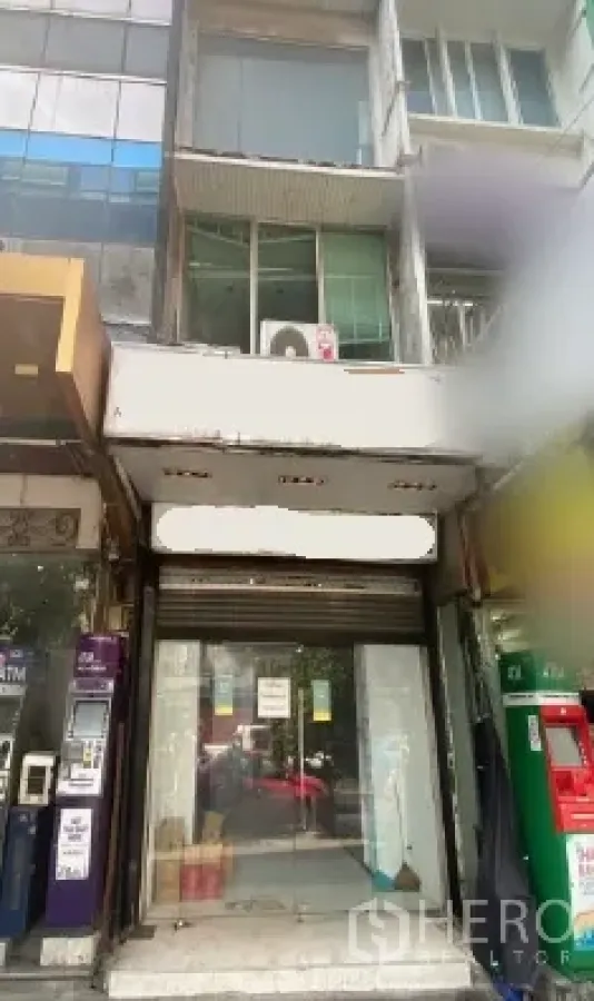 Retail Space for rent in Khlong Toei, Bangkok - Glass-front retail shop facade with roll-up shutter between neighboring units in a high-footfall lane.