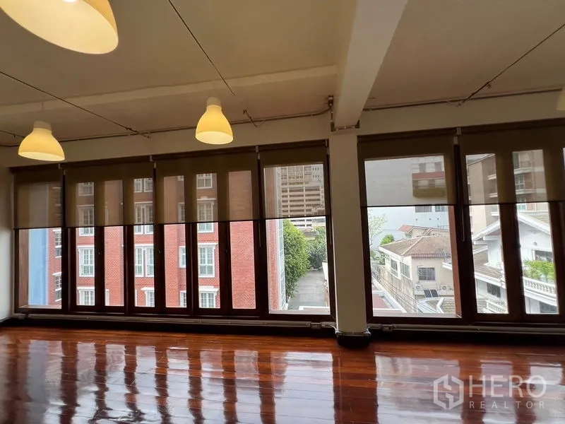 Office Space for rent in Watthana, Bangkok - Close view of floor-to-ceiling windows overlooking low-rise homes and a red-brick facade.