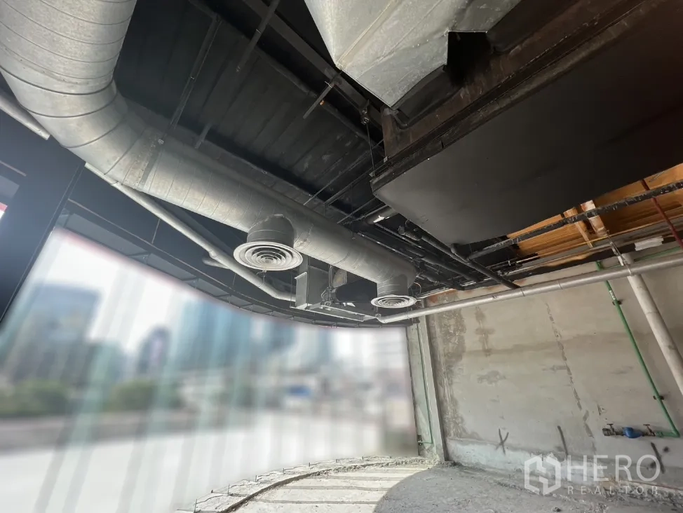Retail Space for rent in Pathum Wan, Bangkok - Curved glass shopfront with visible metal air ducts and city view through the windows.