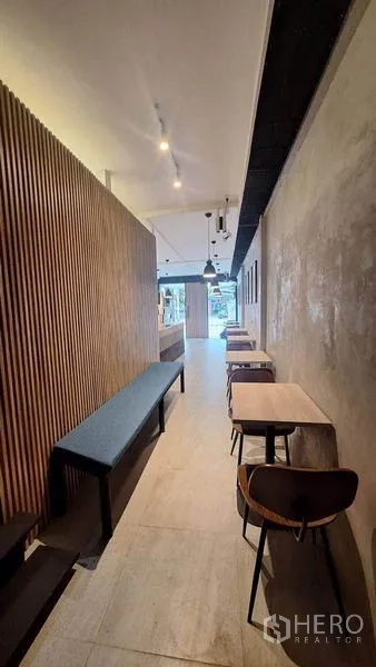Retail Space for rent in Watthana, Bangkok - Narrow retail interior with slatted wood feature wall, small tables, stools and track lights.