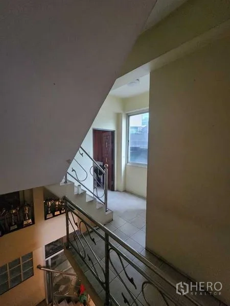Shophouse for rent in Bang Rak, Bangkok - Interior staircase with metal railing leading to a small landing and window.