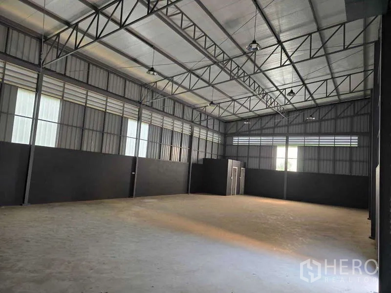 Warehouse for rent in Mueang Samut Sakhon, Samut Sakhon - Large empty warehouse hall with steel walls, truss roof, and service rooms.