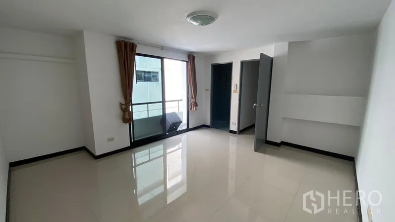 Townhouse for rent in Bang Na, Bangkok - Large bedroom with glossy tile floors, balcony doors and natural light.