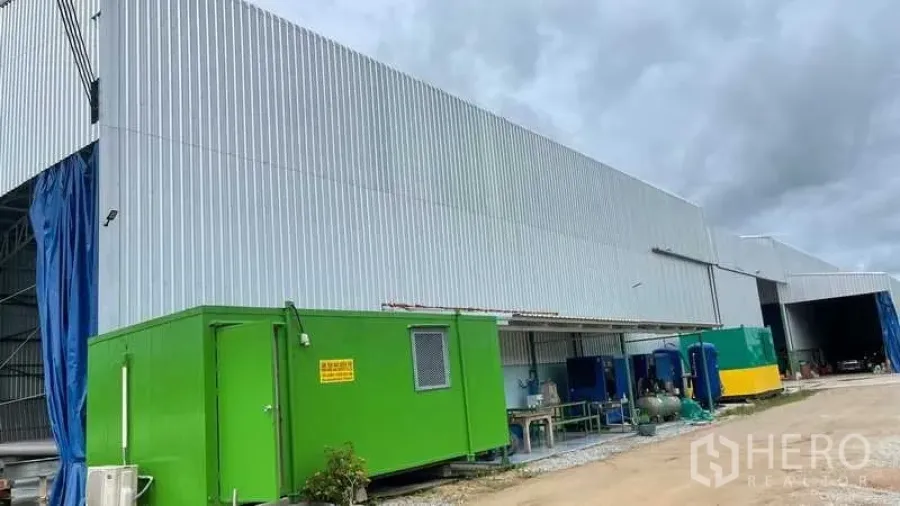 Factory for sale in Nikhom Phatthana, Rayong - Corrugated metal factory exterior with portable utility cabins and service area in Rayong.