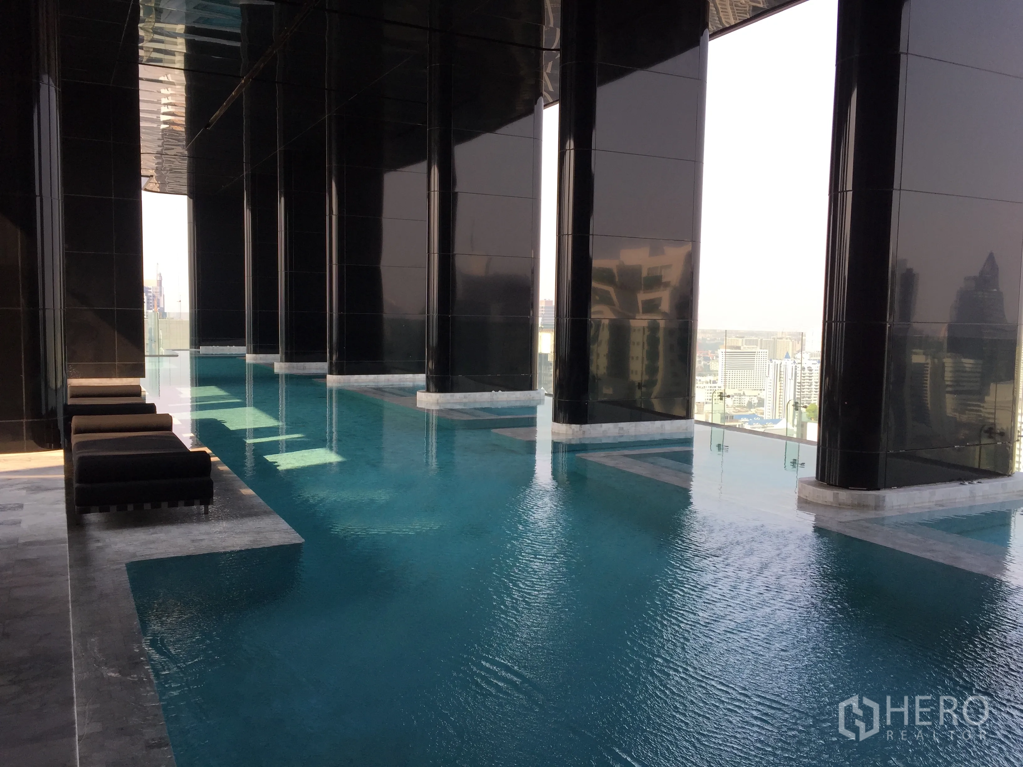 Condominium for sale in Watthana, Bangkok - High-rise infinity swimming pool with loungers and wide city views.
