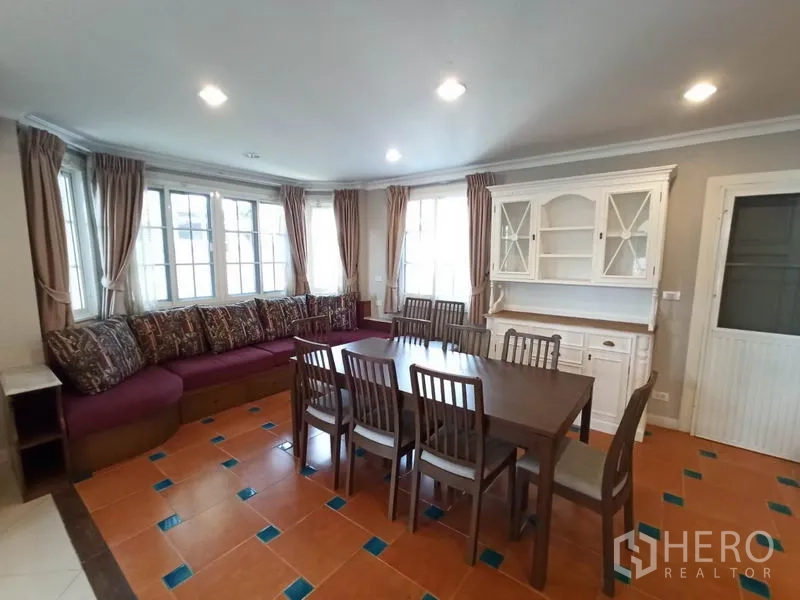 Detached House for rent in Mueang Samut Prakan, Samut Prakan - Corner dining area with eight-seat table, bay-window bench seating and white display cabinet.