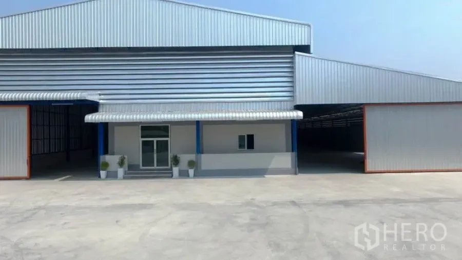 Factory for rent in Mueang Samut Sakhon, Samut Sakhon - Modern metal-clad factory exterior with wide concrete yard and canopy entrance.