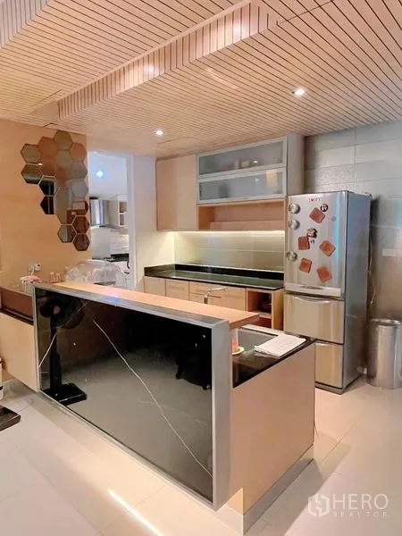 Detached House for rent or sale in Prawet, Bangkok - Contemporary kitchen with island, wooden slat ceiling, stone countertops and stainless refrigerator.