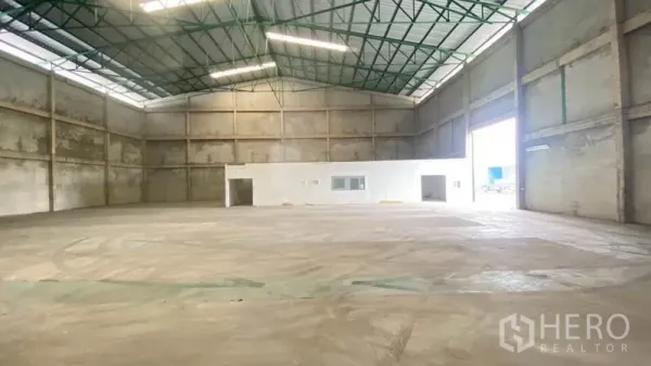 Warehouse for rent in Samut Prakan - Open warehouse floor with high ceiling, large roller door and attached office block.