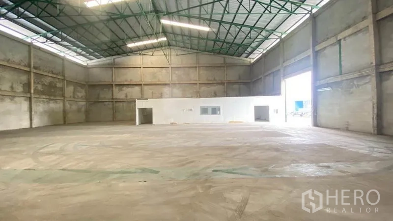 Warehouse for rent in Samut Prakan - Open warehouse floor with high ceiling, large roller door and attached office block.