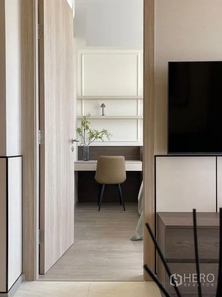Condominium for rent in Pathum Wan, Bangkok - View through a doorway to a compact study with built-in desk, floating shelves and light wood finishes.