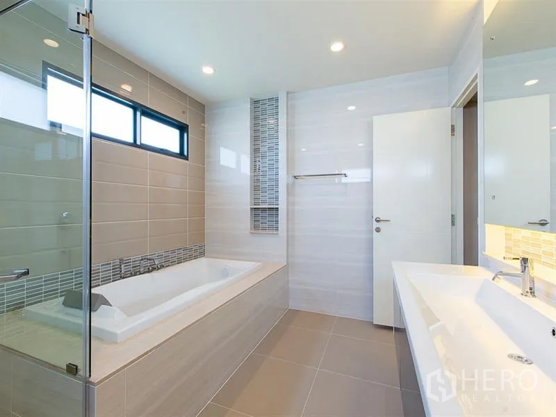 Detached House for rent or sale in Prawet, Bangkok - Contemporary bathroom with soaking tub, glass shower and double vanity.
