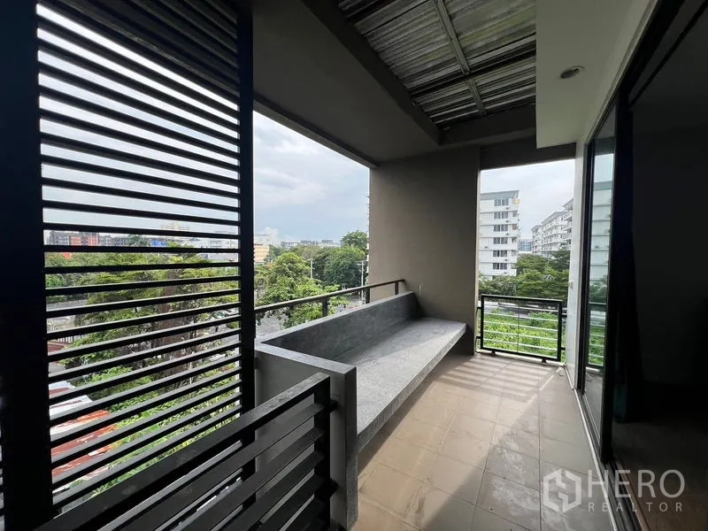 Townhouse for rent or sale in Khlong Toei, Bangkok - Covered balcony with a built-in concrete bench overlooking greenery and buildings.