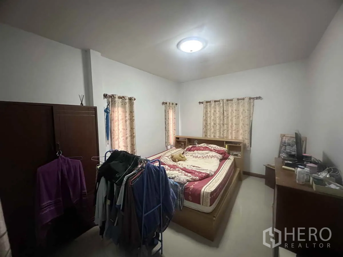 Detached House for sale in Pathum Thani - Spacious master bedroom with double bed, wardrobes and a clothes rack.