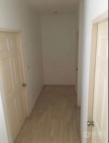 Townhouse for sale in Khlong Toei, Bangkok - Simple upstairs corridor with light wood floors and cream doors.