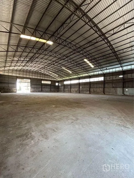 Warehouse for rent in Sam Phran, Nakhon Pathom - Spacious clear-span warehouse interior with high arched steel truss roof, skylights and a concrete floor.