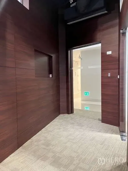 Office Space for rent in Watthana, Bangkok - Entrance corridor with dark wood wall panels, glass door and carpeted floor inside the office.