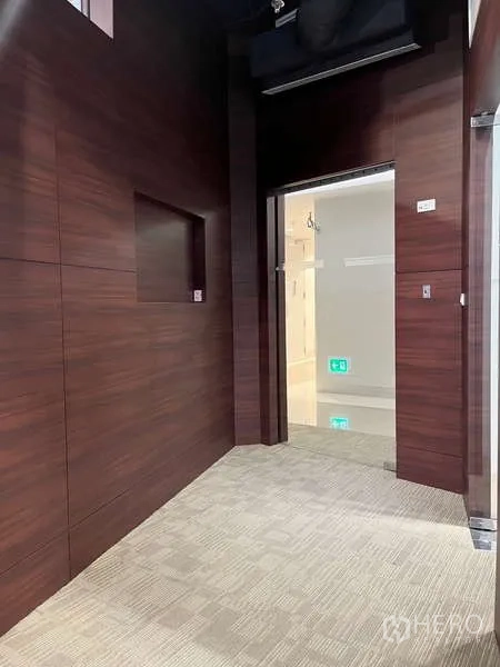 Office Space for rent in Watthana, Bangkok - Entrance corridor with dark wood wall panels, glass door and carpeted floor inside the office.