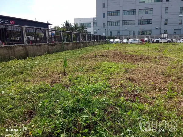 地 出租在Khan Na Yao, Bangkok - 地块近景，已整平，邻黑色商业建筑与边界墙。