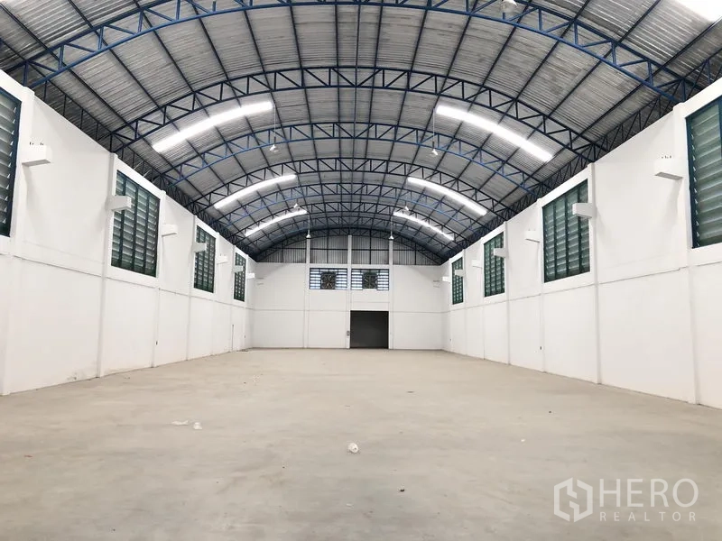 Factory for rent or sale in Bang Sao Thong, Samut Prakan - Open factory floor with high clearance, louvered ventilation windows, and a large entry door.