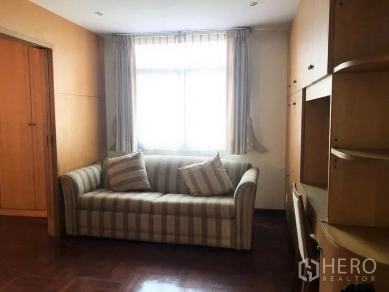 Detached House for sale in Mueang Samut Prakan, Samut Prakan - Small sitting room with striped sofa and built-in cabinets and shelves.