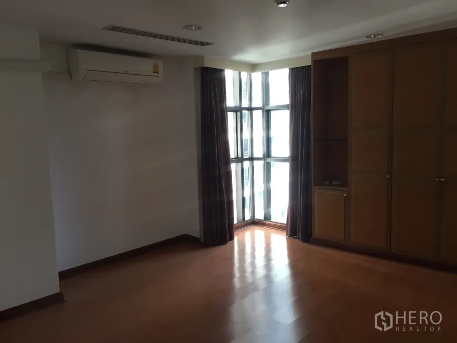 Condominium for rent in Pathum Wan, Bangkok - Sunlit corner bedroom with floor-to-ceiling windows, built-in wardrobe and wood floors in a Pathum Wan condo.
