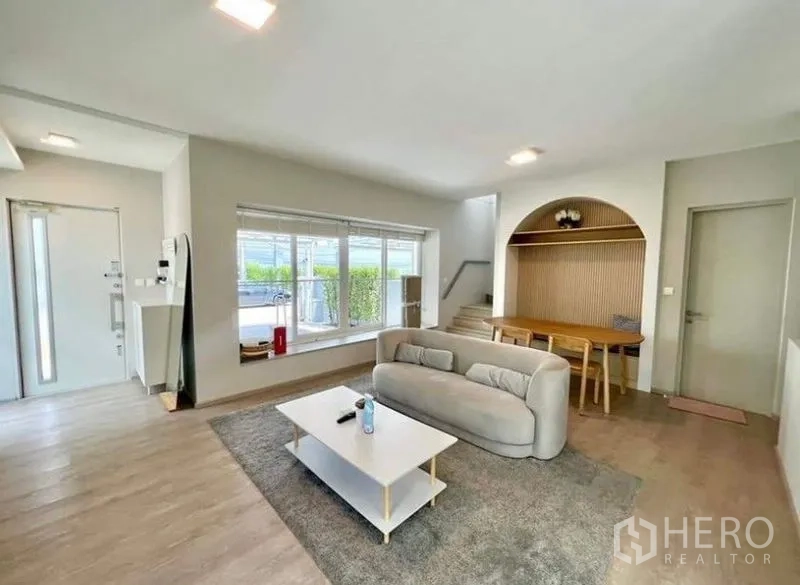 Detached House for rent - Living area with sofa, wide windows, staircase and under-stair storage.