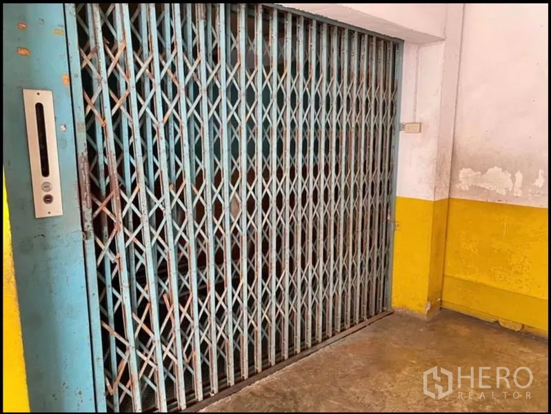 Factory for rent in Chom Thong, Bangkok - Old-style cargo lift with a collapsible metal gate inside the building.