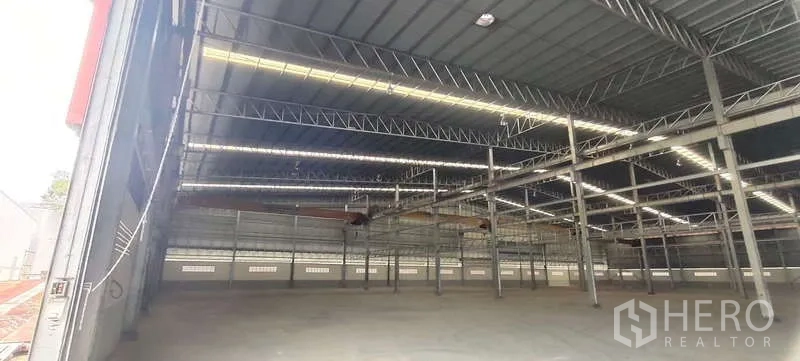 Warehouse for rent in Nikhom Phatthana, Rayong - Spacious warehouse interior with high steel truss roof, skylight strips and open concrete floor.