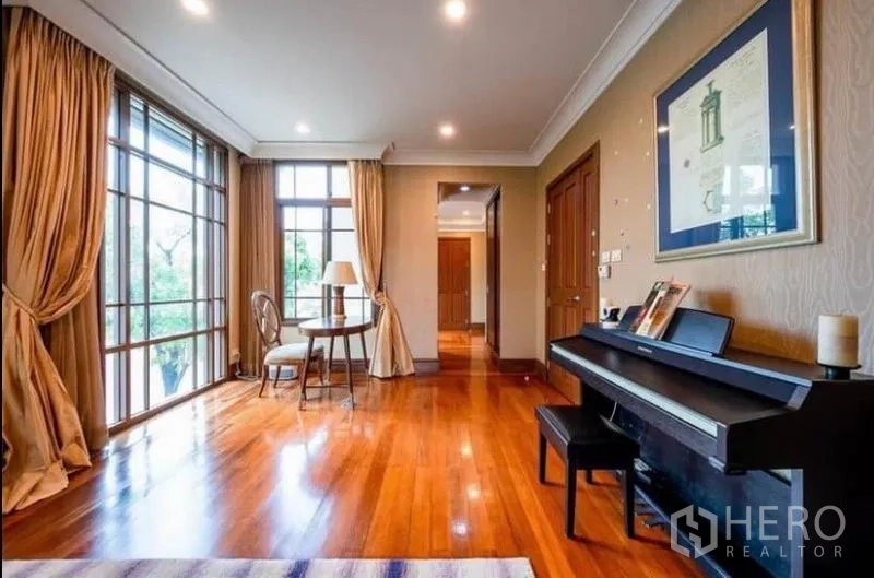 Detached House for rent in Khlong Toei, Bangkok - Bright sitting area with floor-to-ceiling windows, hardwood floors, curtains and an upright piano.