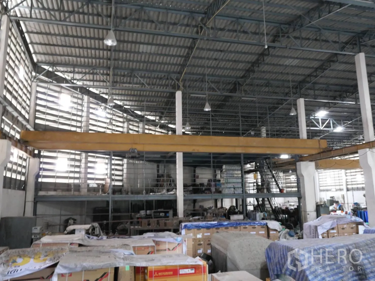 Factory for rent or sale in Bang Khun Thian, Bangkok - Storage zone under mezzanine with boxes and loading area inside the factory.