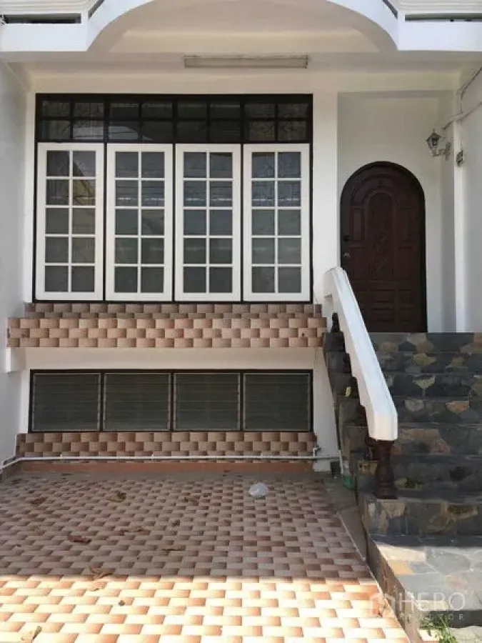 Townhouse for rent in Phra Khanong, Bangkok - Townhouse facade with stone steps, arched entry and white-framed windows.