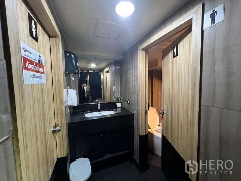 Shophouse for rent or sale in Khlong Toei, Bangkok - Restroom corridor with sink, mirrors and separate male and female toilet doors.