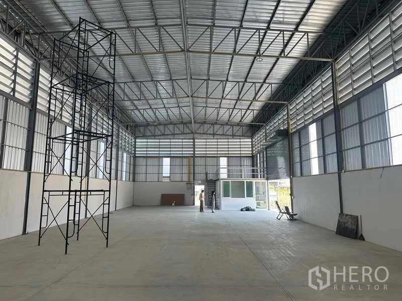 Warehouse for rent in Bang Bua Thong, Nonthaburi - Central view across the spacious warehouse toward the front entry with scaffolding installed.