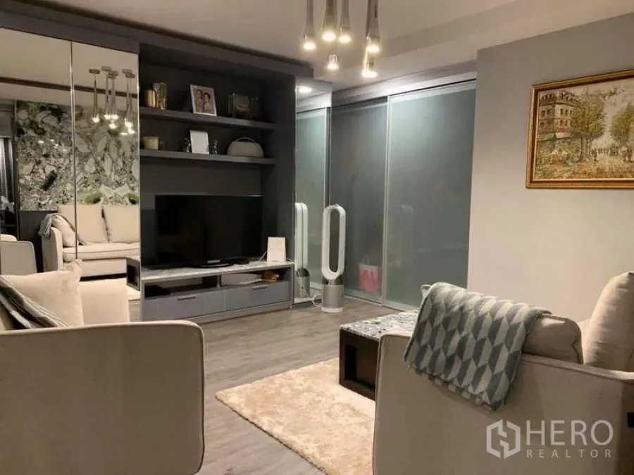 Condominium for sale in Khlong Toei, Bangkok - Living room with built-in TV wall, shelving, frosted glass sliding doors and modern pendant lights.