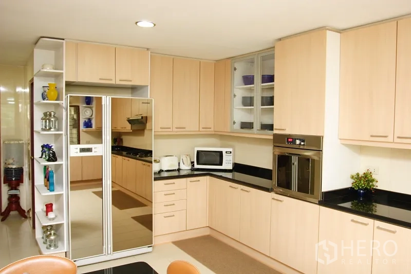Condominium for rent in Khlong Toei, Bangkok - Modern separate kitchen with light wood cabinetry, black stone counters, built‑in oven and side‑by‑side refrigerator.