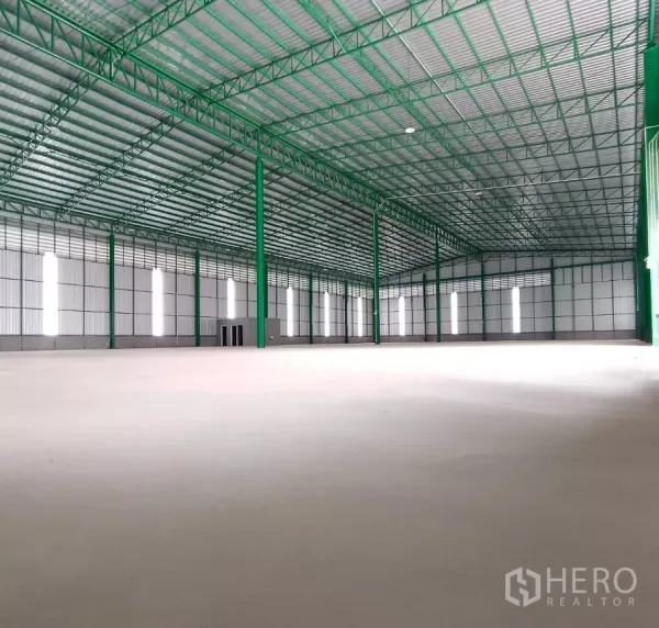 Warehouse for rent in Bang Bon, Bangkok - Expansive clear-span warehouse floor with high ceiling, green steel trusses and daylight panels.