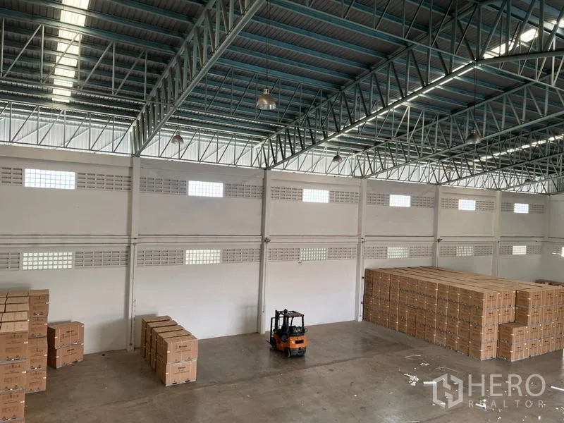 Warehouse for rent in Lat Krabang, Bangkok - Wide warehouse floor seen from above with a forklift and palletized boxes beneath skylights.