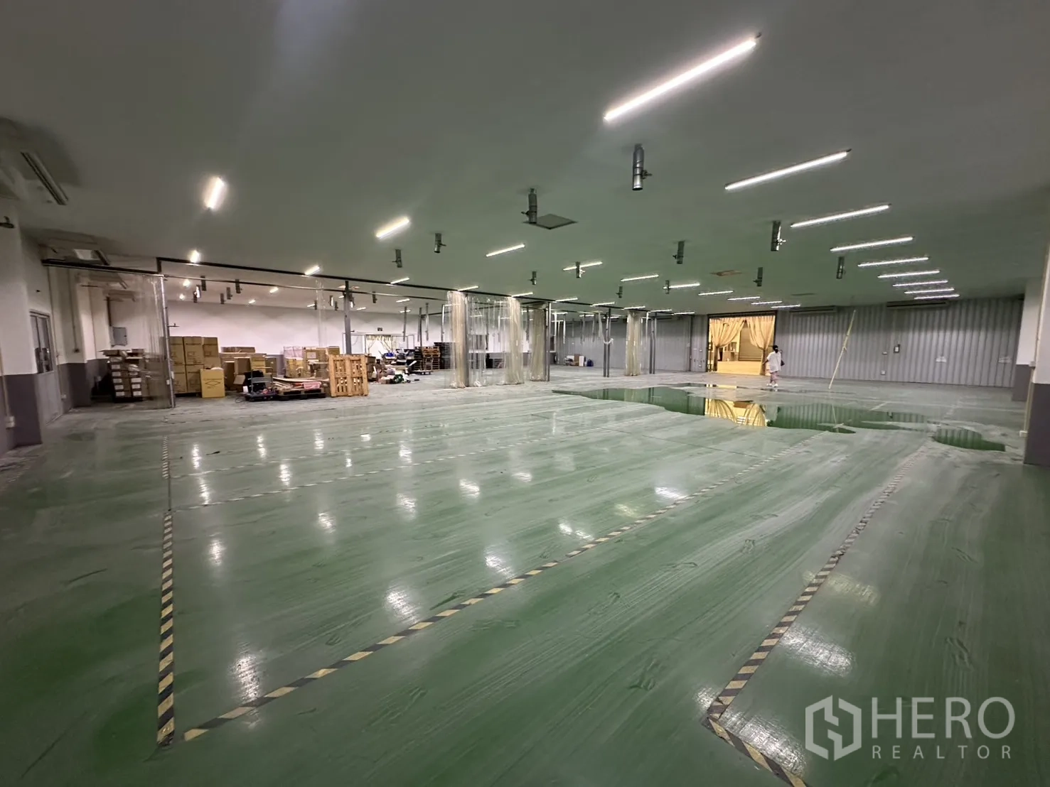 Factory for rent - Large production hall with storage area and equipment at the far end.