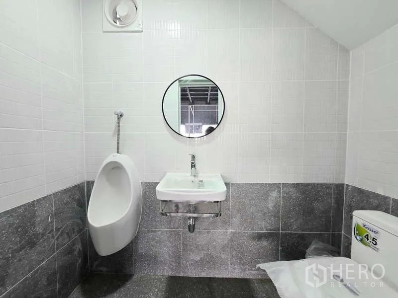 Warehouse for rent in Wang Thonglang, Bangkok - Clean tiled restroom with sink, mirror, urinal and toilet inside the warehouse.