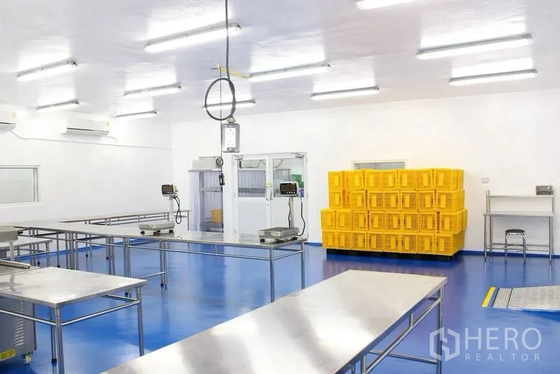 Factory for rent or sale in Krathum Baen, Samut Sakhon - Processing area with yellow plastic crates, weighing scales, and stainless worktables.