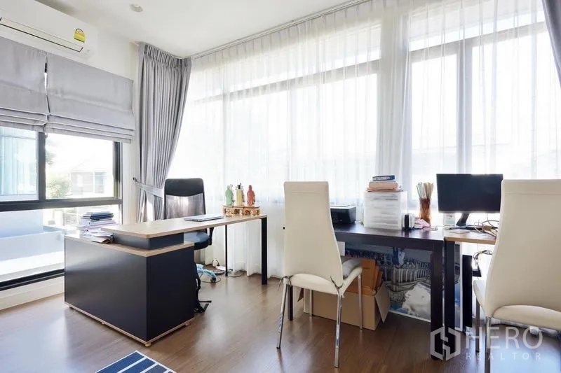 Detached House for rent or sale in Bang Kapi, Bangkok - Light-filled study room with two workstations beside tall windows and wood flooring.