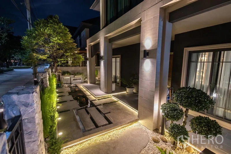 บ้าน ขายในPak Kret, Nonthaburi - สวนหน้าบ้านตกแต่งสวย ทางเดินแผ่นปูน บ่อน้ำ และไฟทางเดินยามค่ำ