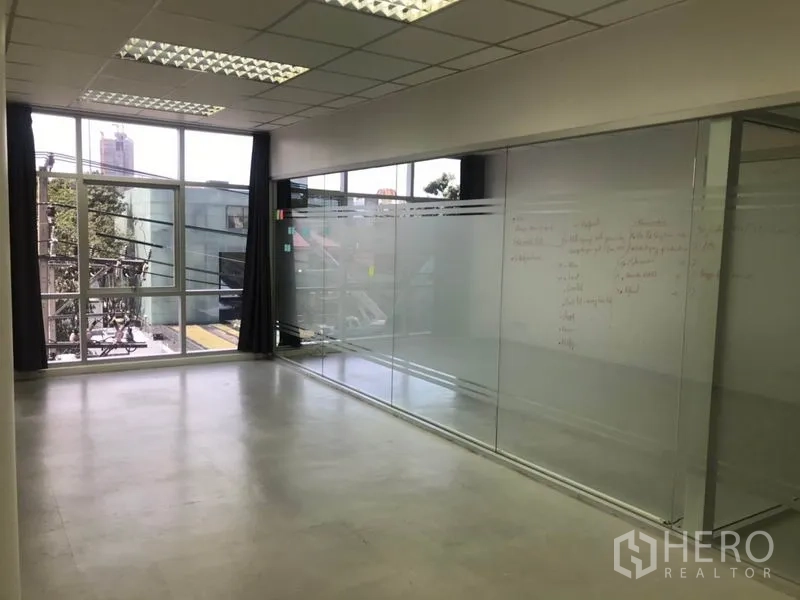 Office Space for rent in Khlong Toei, Bangkok - Bright office zone featuring floor-to-ceiling windows and a long frosted glass wall.