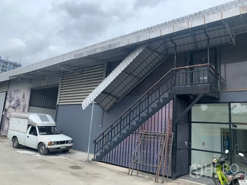 Warehouse for rent in Suan Luang, Bangkok - Warehouse exterior with metal staircase, canopy roof and parking area
